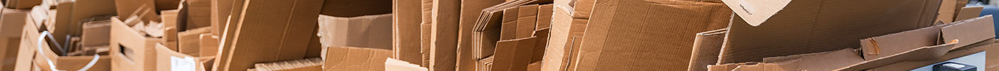 rows of cardboard boxes stacked outside in the sunshine, packed together, ready to be taken away for recycling