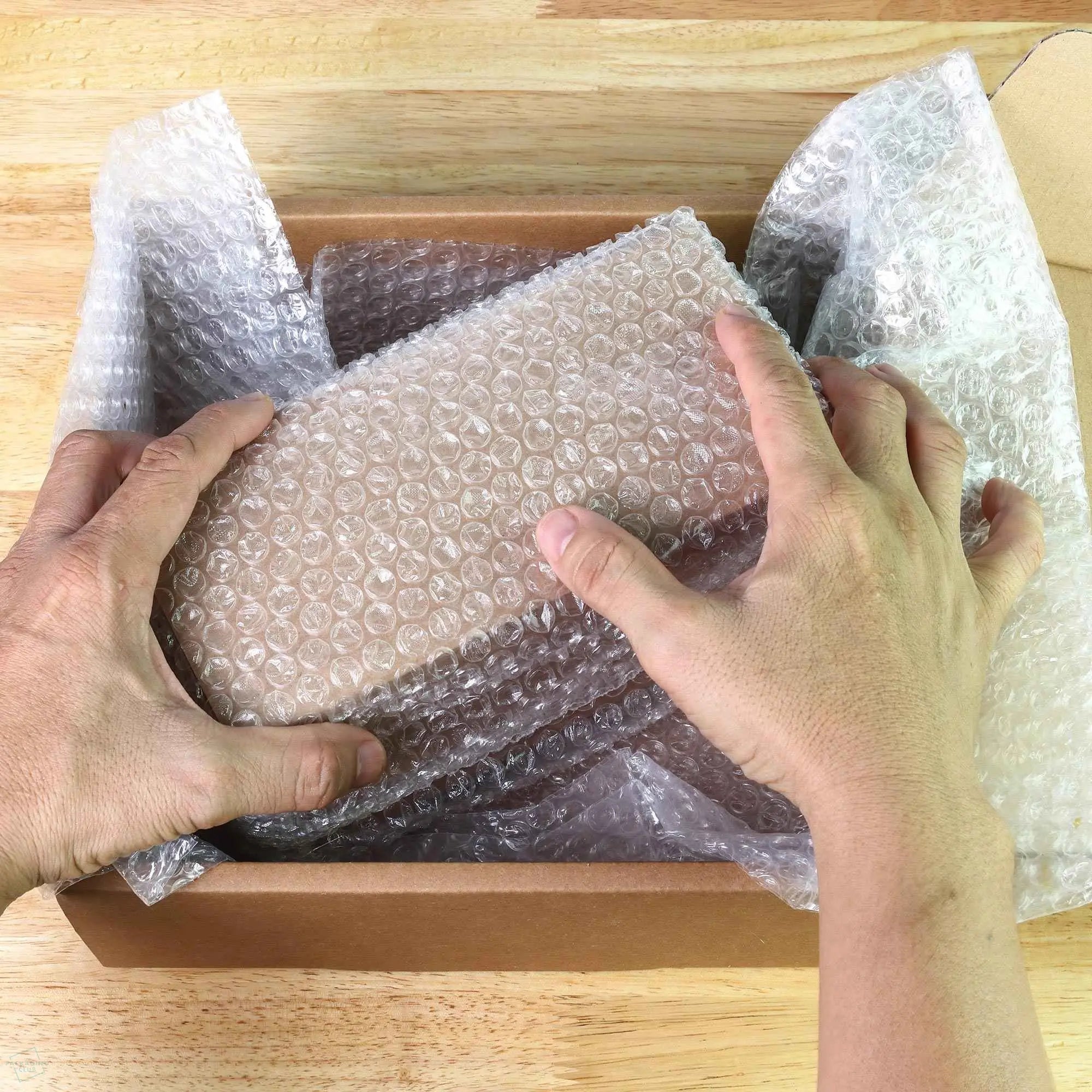 how to use bubble wrap - mage of a man placing a product wrapped in bubble wrap into a cardboard box