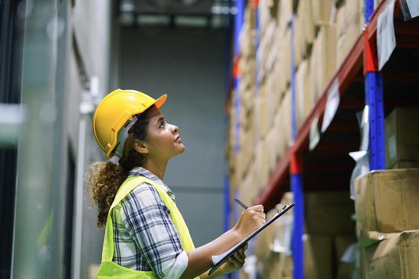 Image of a lady checking inventory in a large warehouse, representing consolidating supply of packaging in jobs focused in GNFR