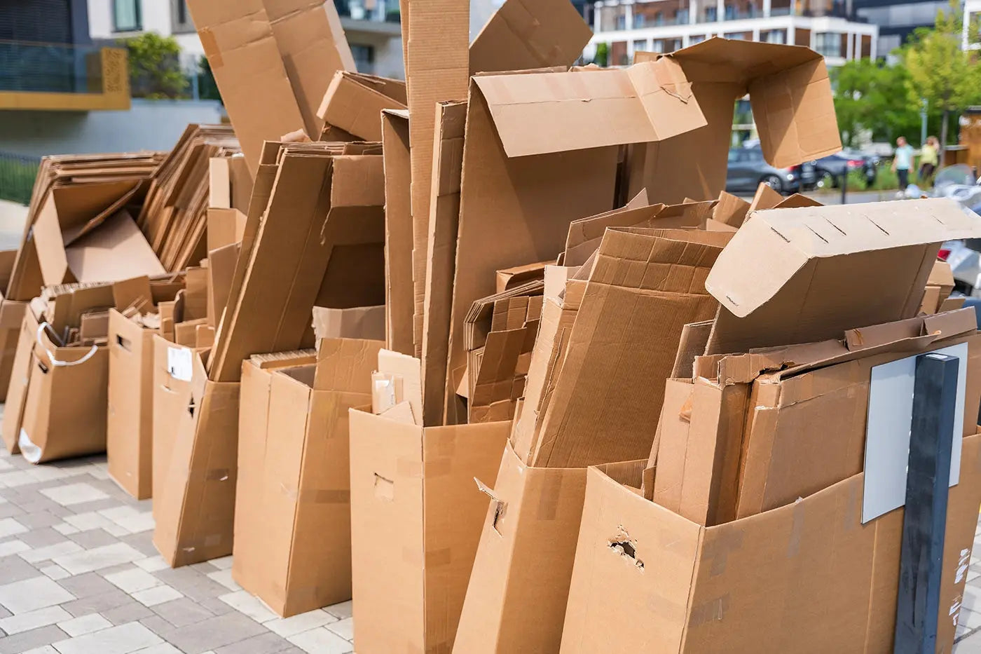 rows of cardboard boxes stacked outside in the sunshine, packed together, ready to be taken away for recycling