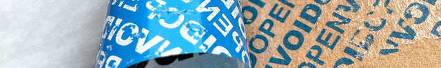 Paper-based tamper evident sealing strip with 'OPEN VOID' text on a cardboard surface